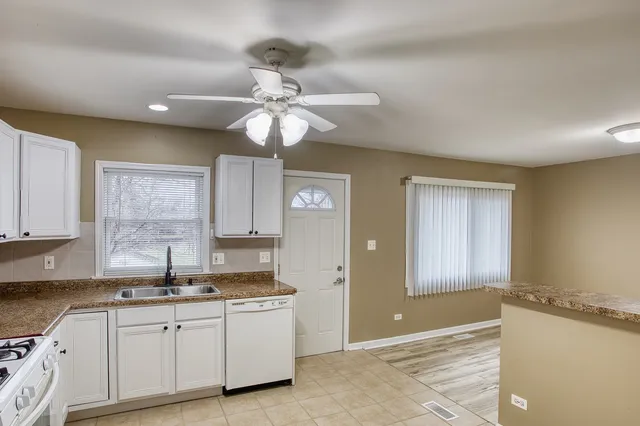 a kitchen with granite countertop a sink cabinets stainless steel appliances and a window