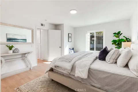 a bedroom with a large bed a potted plant and a window