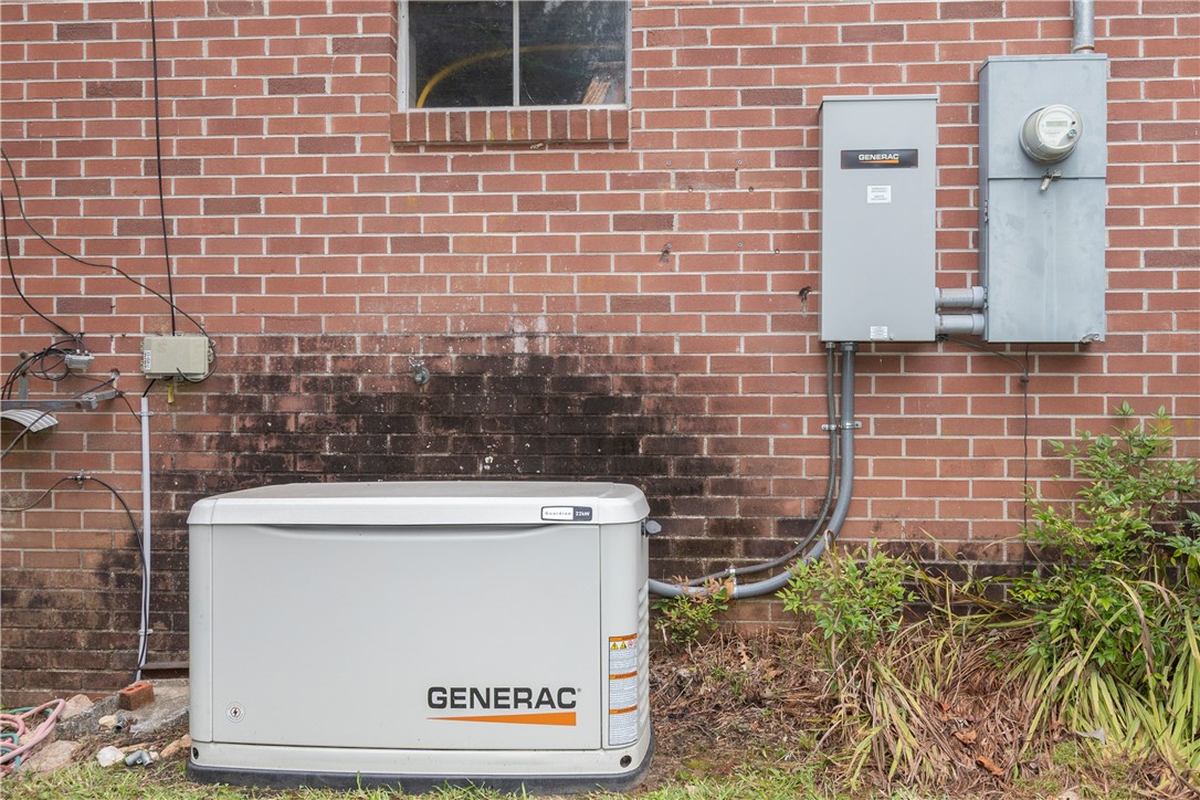 118 Blair Road Belton, SC 29627 - Photo 47 of 49 A whole-house backup generator system is installed against a classic brick exterior wall.