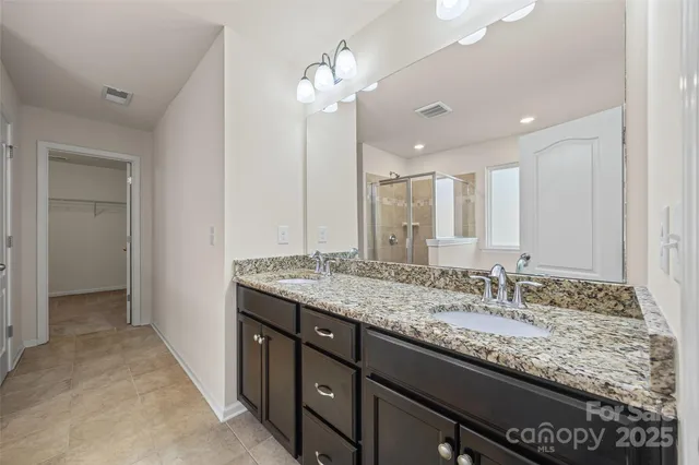 a bathroom with a granite countertop double vanity sink and a mirror