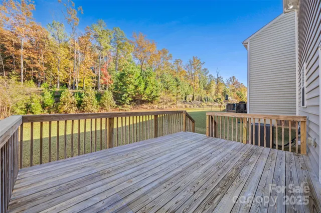 a view of a deck with wooden floor and fence with a large tree