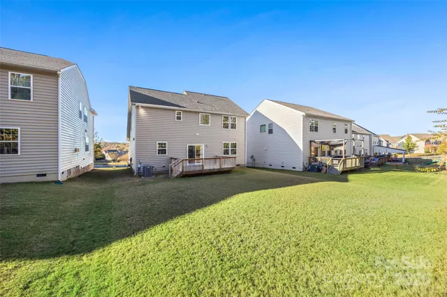 a view of a white house in front of a big yard with potted plants