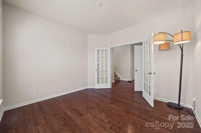 a view of an empty room with wooden floor and a bathroom