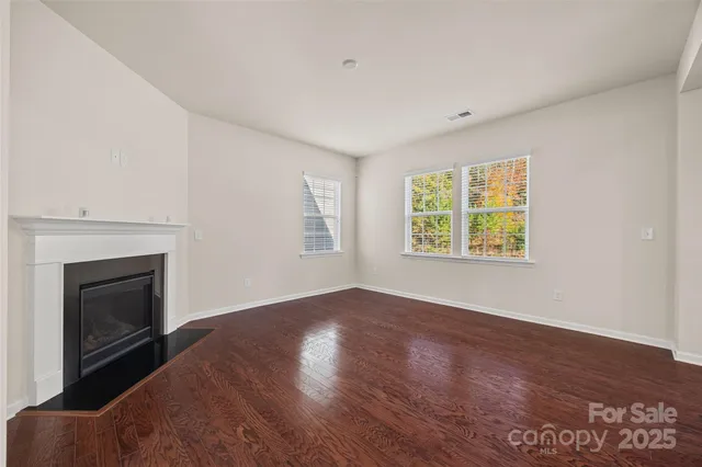 an empty room with windows and fireplace