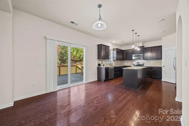 a view of kitchen with granite countertop stainless steel appliances and wooden floor