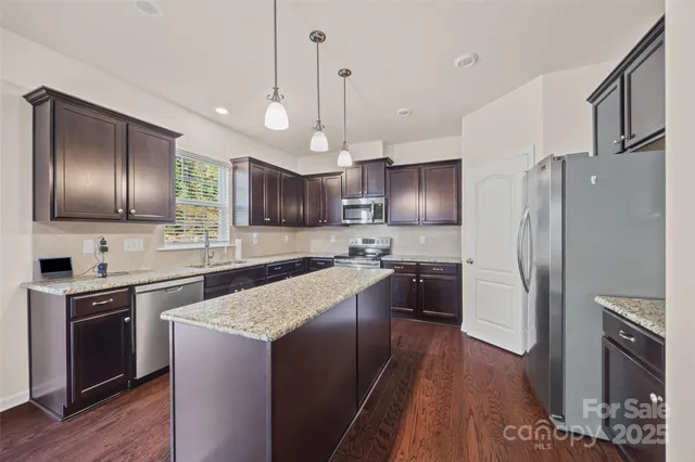 a kitchen with granite countertop stainless steel appliances cabinets a sink a stove a refrigerator and a center island