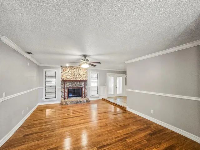 a view of an empty room with a fireplace and windows
