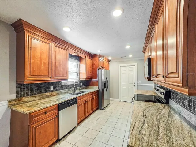 a large kitchen with stainless steel appliances granite countertop a sink and a stove