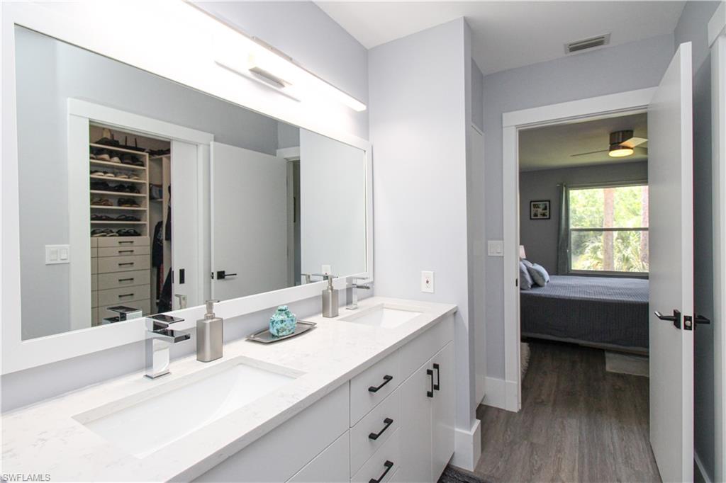 225 Robin Hood Circle, Unit 203 Naples, FL 34104 - Photo 42 of 50 Bathroom featuring ceiling fan, double sink vanity, and wood-type flooring