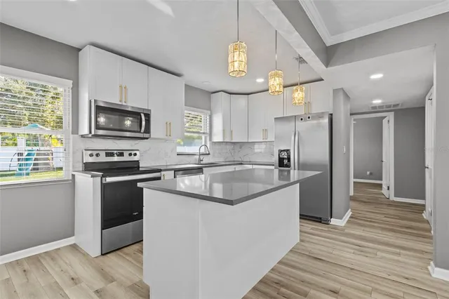 a kitchen with granite countertop a sink cabinets stainless steel appliances and a window