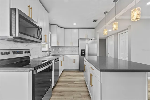 a large kitchen with stainless steel appliances granite countertop a stove a refrigerator and a microwave