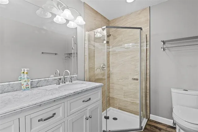 a bathroom with a granite countertop sink a toilet and shower