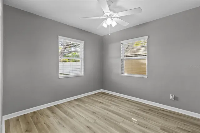 a view of empty room with wooden floor and fan