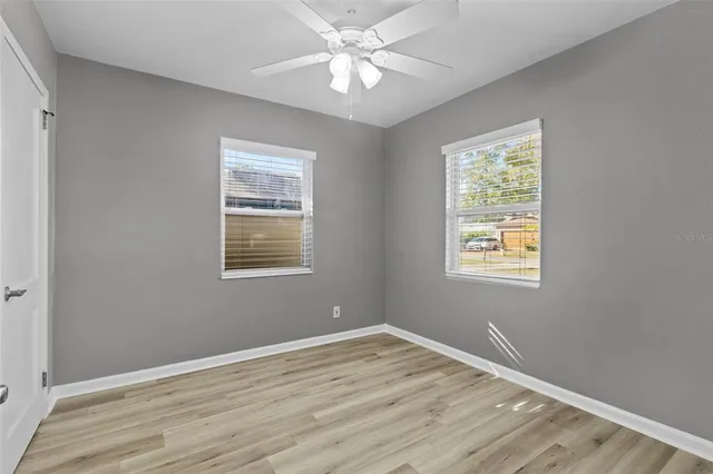 a view of empty room with wooden floor and fan