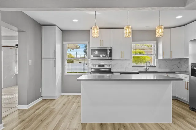 a kitchen with stainless steel appliances granite countertop a sink a stove a refrigerator cabinets and wooden floor