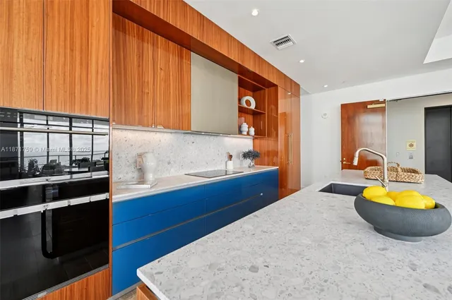 a kitchen with stainless steel appliances granite countertop a table chairs and a refrigerator