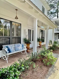 a view of a patio with table and chairs potted plants and floor to ceiling window