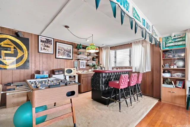 a kitchen with stainless steel appliances kitchen island granite countertop a refrigerator a stove a dining table and chairs with wooden floor