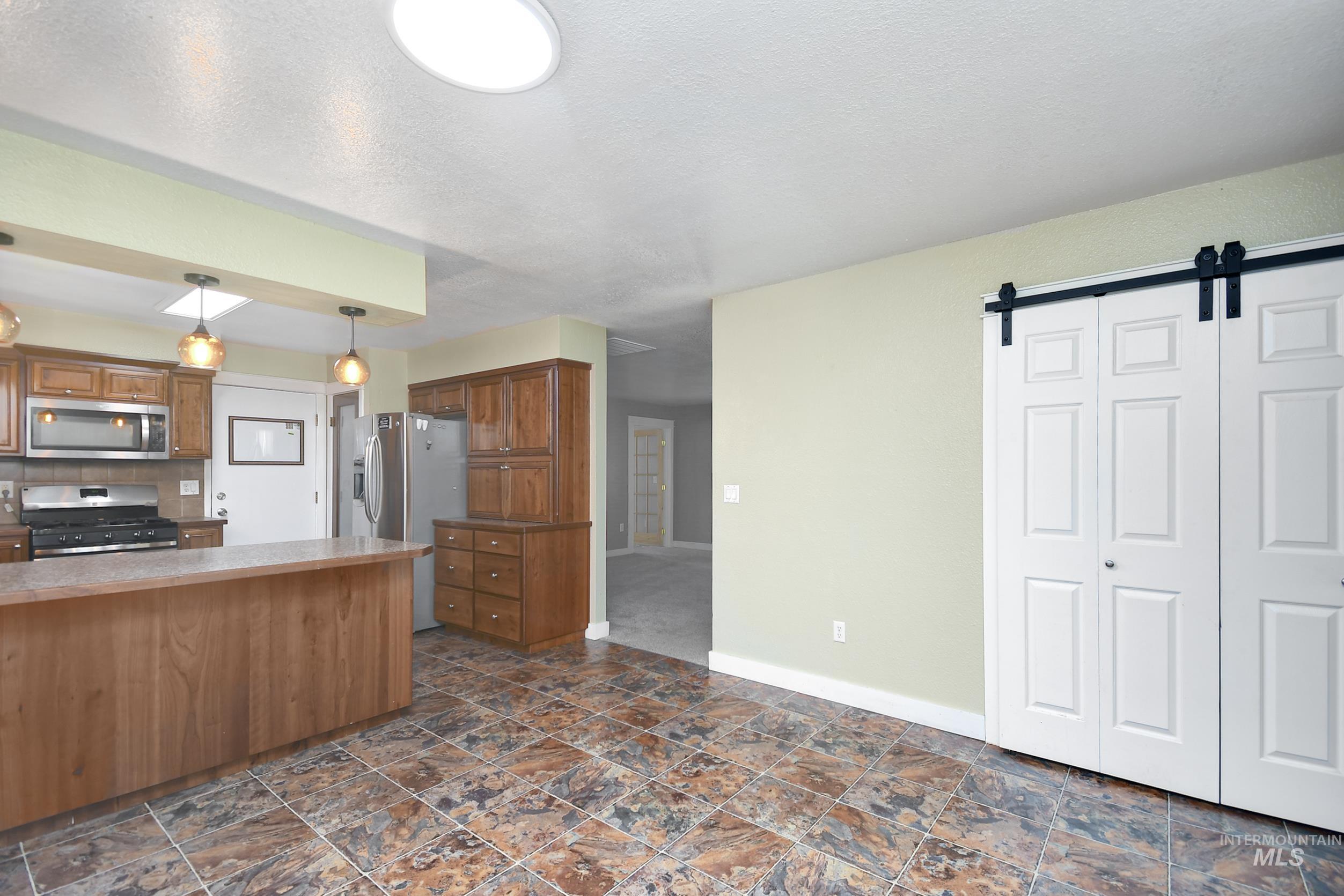 1108 East Ustick Road Caldwell, ID 83607 - Photo 11 of 30 Kitchen space featuring tile flooring, wood-finish cabinetry, and stainless steel appliances