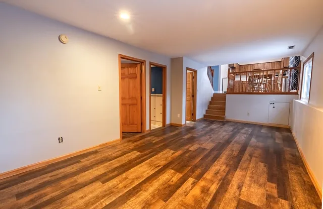 a view of an empty room with window and wooden floor