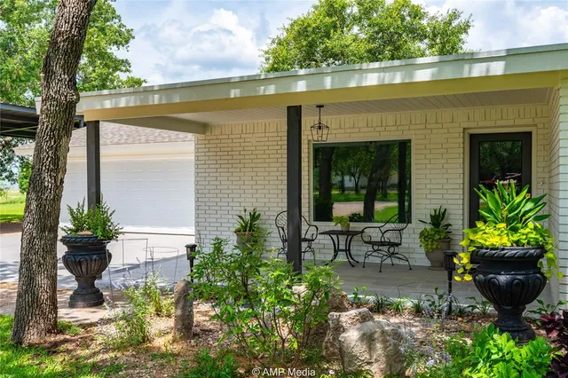 a view of a patio with table and chairs potted plants and large tree