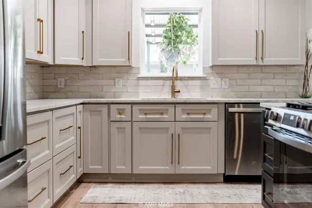 a kitchen with stainless steel appliances granite countertop a refrigerator a sink dishwasher a stove and white cabinets with wooden floor