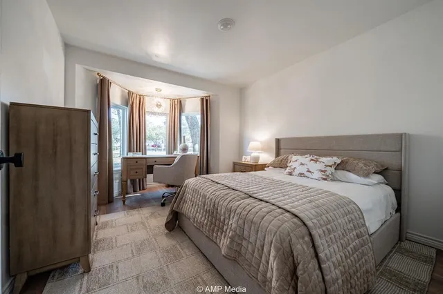 a bedroom with a large bed a flat screen tv and a large window