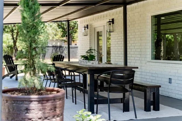 a view of a patio with table and chairs potted plants and a large tree