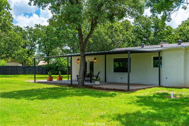 a backyard of a house with large trees and plants