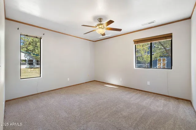 an empty room with a ceiling fan and carpet