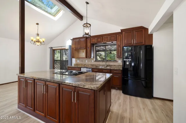 a kitchen with stainless steel appliances granite countertop a refrigerator a sink and wooden floors