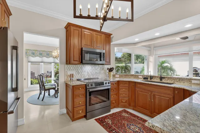 a kitchen with stainless steel appliances granite countertop a refrigerator a stove and a sink