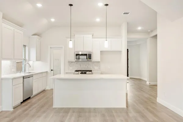 a kitchen with kitchen island a white counter top space appliances and cabinets