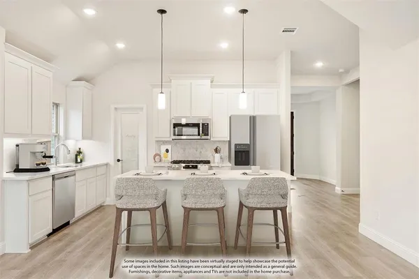 a large kitchen with stainless steel appliances a refrigerator a sink dishwasher a oven with white cabinets and wooden floor