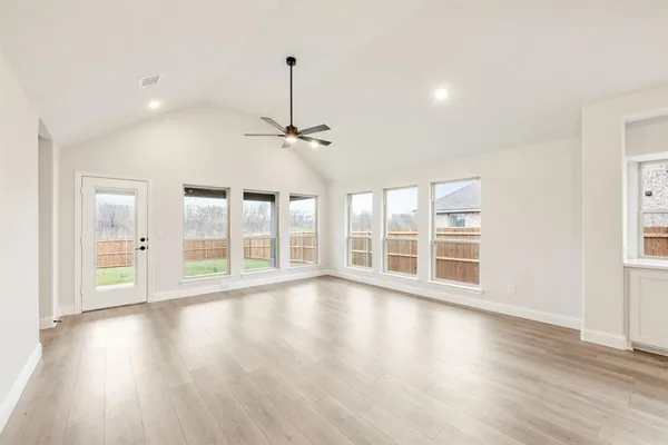 a view of an empty room with kitchen and window