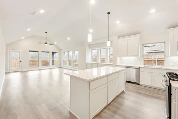 a large kitchen with granite countertop a stove a sink a center island and cabinets