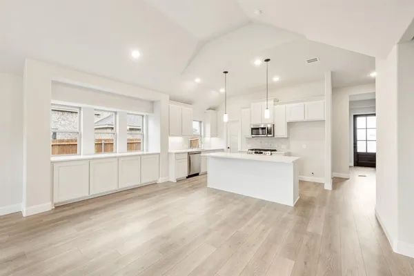 a large white kitchen with kitchen island a sink a center island stainless steel appliances and a cabinets