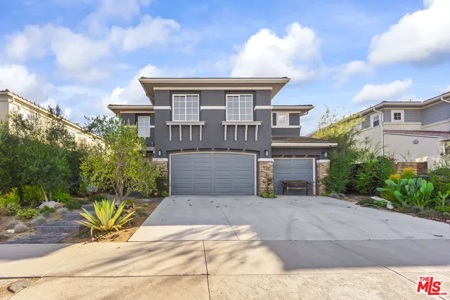 a view of a house with potted plants and a bench