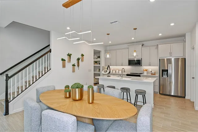 a kitchen with stainless steel appliances kitchen island granite countertop a stove a sink a dining table and chairs with wooden floor