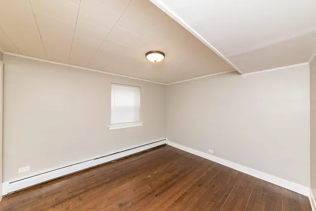 a view of an empty room with wooden floor with windows