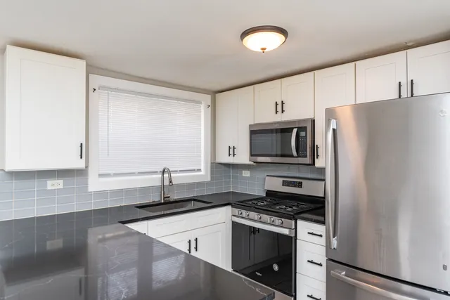 a kitchen with stainless steel appliances white cabinets and a refrigerator