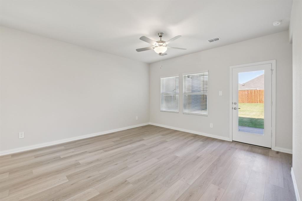 1720 Arches Road Anna, TX 75409 - Photo 11 of 31 an empty room with wooden floor chandelier fan and windows