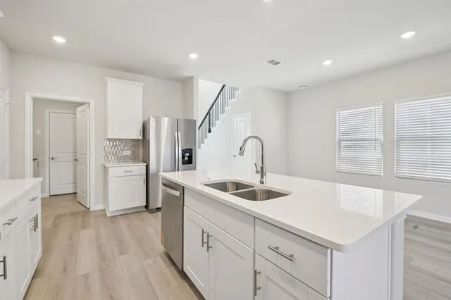 a kitchen with white cabinets and sink