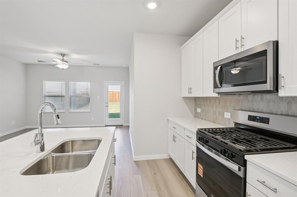 1720 Arches Road Anna, TX 75409 - Photo 6 of 31 a kitchen with white cabinets a sink stove and microwave