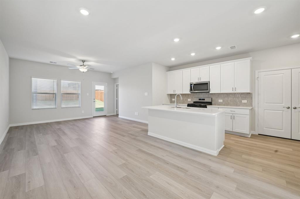 1720 Arches Road Anna, TX 75409 - Photo 7 of 31 a kitchen with granite countertop white cabinets and wooden floor