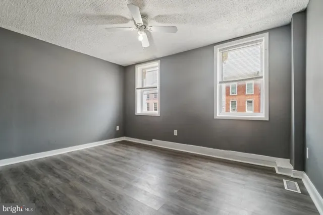 a view of an empty room with a window and wooden floor