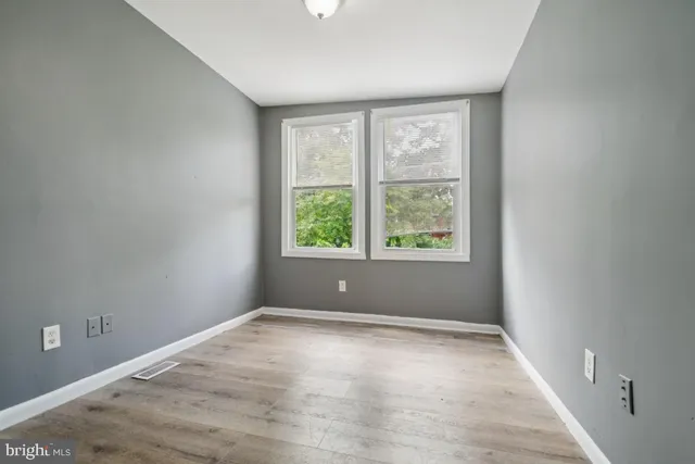 an empty room with wooden floor and windows