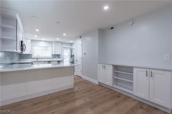 a large white kitchen with wooden floors and white cabinets