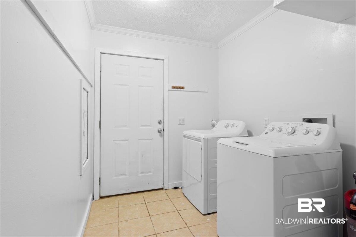 6971 March Road Theodore, AL 36582 - Photo 17 of 26 Clothes washing area featuring washing machine and clothes dryer, ornamental molding, laundry area, and light tile patterned floors