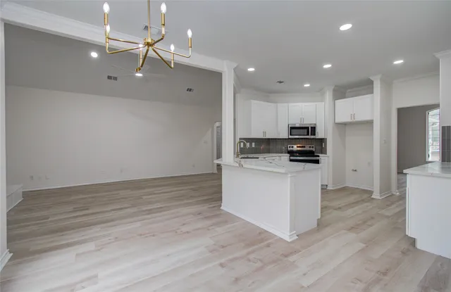 a kitchen with granite countertop a refrigerator oven a sink and white cabinets